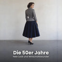 Frau im grauen taillierten Jackett und weiten dunkelblauen Rock im New Look Stil der 1950er Jahre mit weißen Handschuhen