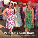 Zwei Frauen in geblümten Sommerkleidern vor dem Verkaufsstand mit Kleiderständern und Schneiderpuppe auf den Rockabilly Days