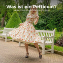 Frau im geblümten Swingkleid der 1950er Jahre dreht sich, darunter blitzt der Petticoat hervor