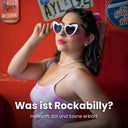 Frau mit herzförmiger Sonnenbrille, Perlenkette und rosa kariertem Trägerkleid vor einer roten Wand mit alten Blechschildern