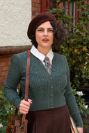 Frau in grünem Vintage-Strickcardigan über weißer Bluse mit Krawatte und brauner Baskenmütze, Kollektion Cardigans